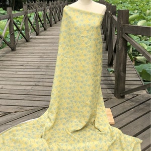 May include: A yellow fabric with a light blue floral pattern. The fabric is draped over a wooden railing.