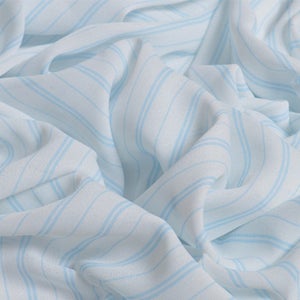 May include: White fabric with thin, light blue stripes. The fabric is creased and folded.