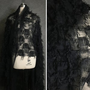 May include: Black sheer fabric with a textured, fringed design. The fabric has a grid pattern with square-shaped fringes.