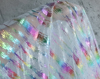 May include: White sheer fabric with iridescent rainbow stripes. The fabric has a mesh texture.