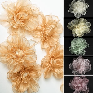 May include: A set of eight sheer fabric flowers in various colors, including beige, cream, light green, pink, and purple. The flowers are layered and have a delicate, ruffled texture.