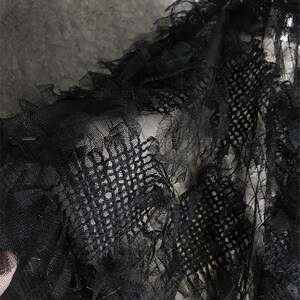 May include: Black sheer fabric with a delicate, ruffled texture. The fabric has a fine mesh pattern and a slightly distressed look.