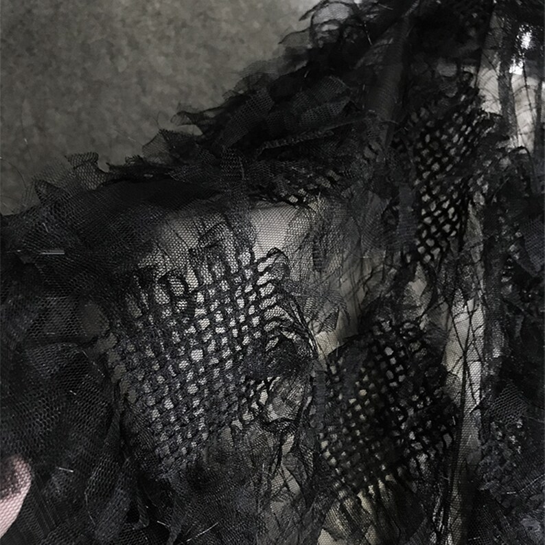 May include: Black sheer fabric with a delicate, ruffled texture. The fabric has a fine mesh pattern and a slightly distressed look.