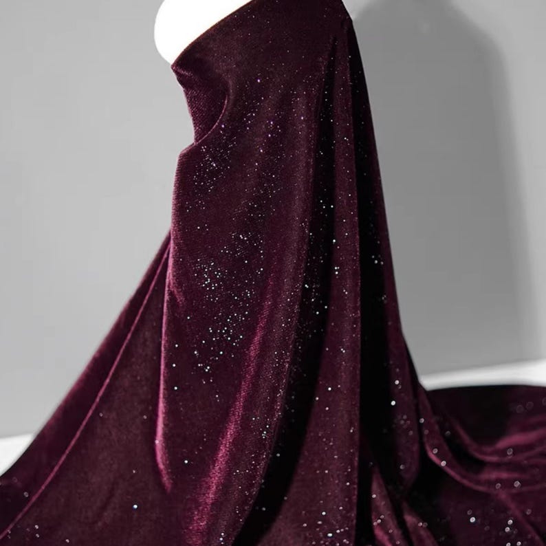 May include: Burgundy velvet fabric with a subtle sparkle. The fabric has a soft, luxurious feel and is perfect for a variety of projects.