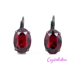 Peut inclure: Une paire de boucles d'oreilles avec une finition en métal foncé et des pierres précieuses rouges de forme ovale.