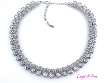 May include: A silver necklace with a twisted chain design and clear rhinestones. The necklace is about 16 inches long and has a lobster clasp closure.