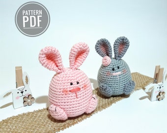 May include: Two crocheted bunny amigurumi toys, one pink and one gray, with embroidered facial features. The bunnies are sitting on a burlap surface. The text "PATTERN PDF" is visible in the top left corner of the image.