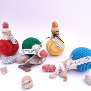 Puede incluir: Cuatro botellas de poci&oacute;n de crochet con etiquetas que dicen "Poci&oacute;n #1", "Poci&oacute;n #2", "Poci&oacute;n #3" y "Poci&oacute;n #4". Las botellas son rojas, verdes, amarillas y azules.