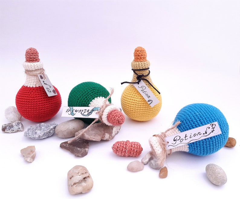 Puede incluir: Cuatro botellas de poci&oacute;n de crochet con etiquetas que dicen "Poci&oacute;n #1", "Poci&oacute;n #2", "Poci&oacute;n #3" y "Poci&oacute;n #4". Las botellas son rojas, verdes, amarillas y azules.