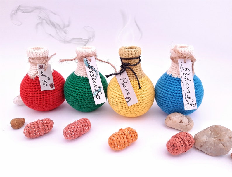 Puede incluir: Cuatro botellas de poci&oacute;n de crochet con etiquetas que dicen "Potion #1", "Potion #2", "Potion #3" y "Potion #4". Las botellas son rojas, verdes, amarillas y azules.