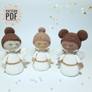 May include: Three crocheted angel ornaments with white dresses, gold sashes, and brown hair. The angels have different hairstyles, including a bun and pigtails.