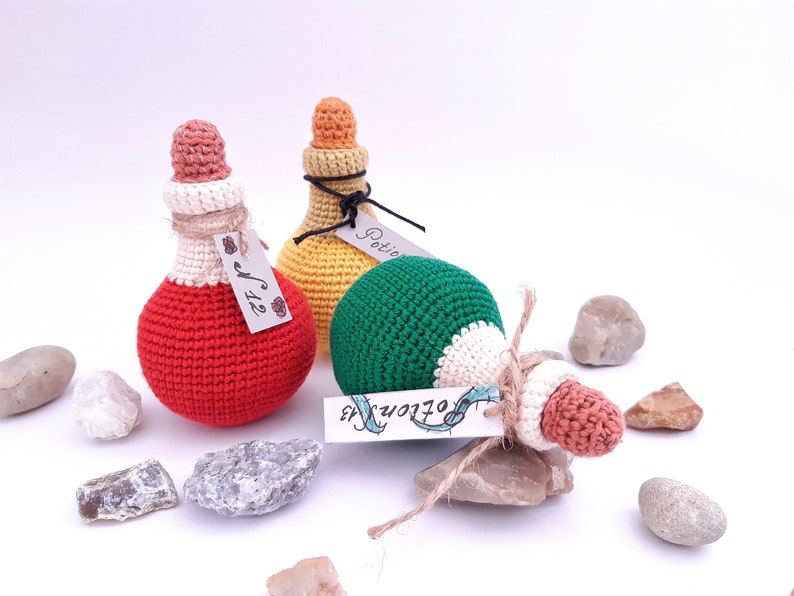 Puede incluir: Tres botellas de poci&oacute;n de crochet con tapones de corcho y etiquetas. Las botellas son roja, amarilla y verde. Las etiquetas dicen "Poci&oacute;n", "Tama&ntilde;o" y "Pociones".