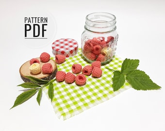 May include: A crocheted raspberry pattern PDF with a jar of crocheted raspberries and a green leaf on a checkered green and white fabric.