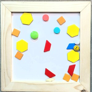 May include: A white magnetic board with various colored shapes and a smiley face sticker. The shapes include hexagons, circles, squares, and triangles in yellow, red, orange, green, and blue.