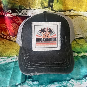 May include: Black and gray trucker hat with a white patch that says "Vacay Mode" with a sunset and palm trees graphic.