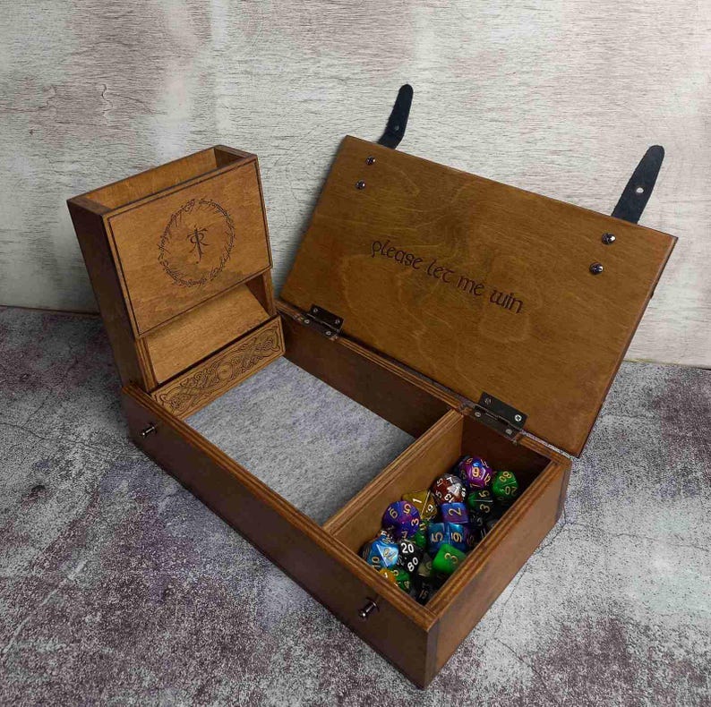 Op de afbeelding: Houten dobbelbox met meerdere compartimenten, waaronder een dobbelbak en een opbergruimte. De doos is gegraveerd met een ontwerp en de tekst "please let me win". Bevat meerdere veelzijdige dobbelstenen.