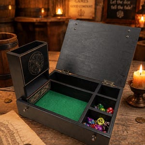 May include: A black wooden dice box with a hinged lid, featuring an integrated vertical dice tower with a circular celestial map design. The interior contains a green felt-lined rolling area and multiple compartments filled with colorful polyhedral dice.