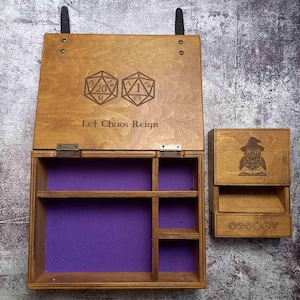 May include: A wooden box with a purple felt interior and a hinged lid. The lid has a design of two dice and the text "Let Chaos Reign". The box is open and there is a smaller wooden box with a dice design on the front.