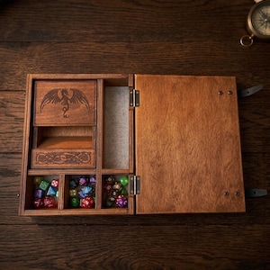 May include: A rectangular wooden box with a hinged lid, featuring a laser-engraved dragon and Celtic knotwork on the interior compartments. The box contains multiple small, multi-coloured polyhedral dice stored in separate sections.