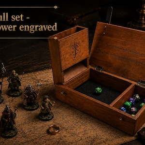 Op de afbeelding: Een houten dobbeldoos en torenset met gegraveerde details. De doos is open en onthult dobbelstenen en een met vilt gevoerd interieur. Miniatuurbeeldjes en een gouden ring zijn ook aanwezig. Tekst op de doos luidt "Full set - box+tower engraved."