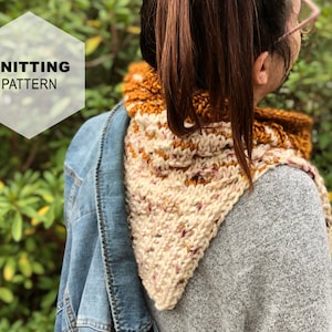 Könnte beinhalten: Ein gestrickter dreieckiger Schal in Weiß-, Rosa- und Brauntönen. Der Schal wird von einer Person mit braunen Haaren und einer Jeansjacke getragen.