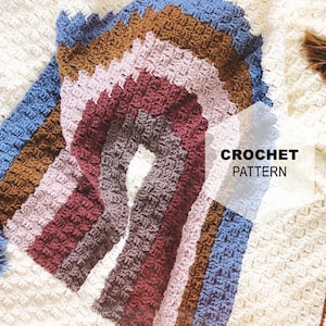 May include: A crochet pattern for a rainbow blanket with a textured stitch. The blanket is made in shades of brown, pink, red, gray, blue, and white. The pattern includes the text "CROCHET PATTERN".