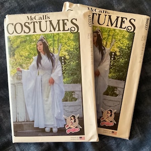 May include: Two McCall's costume pattern envelopes. The patterns feature a person in a white costume with long sleeves and a sword. The envelopes have the word "COSTUMES" in large letters. The size range is listed on the envelope.
