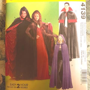 May include: A sewing pattern for three hooded capes. The pattern includes instructions for making a black cape with red lining, a black cape with a spiderweb design, and a purple cape. The pattern is labeled "Easy 2 Hour" and "Facile en 2 Heures".