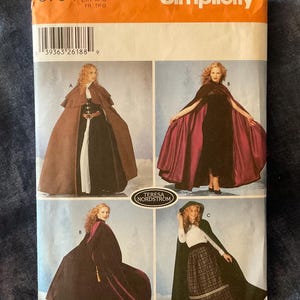 May include: Simplicity sewing pattern 5794 featuring four different cape designs. The pattern includes sizes XS, S, M, and L. The cover shows women wearing capes in various colors and styles, including a brown cape with a belt.