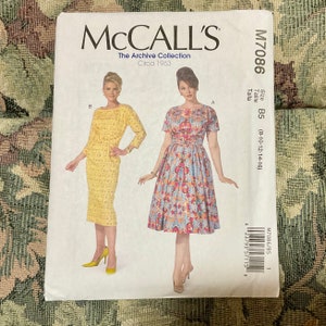 May include: Vintage McCall's sewing pattern for a dress, circa 1963. The pattern is for size B5 (8-10-12-14-16) and features two different styles of dresses, one with a fitted silhouette and the other with a full skirt.