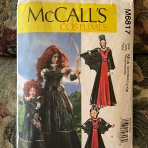 May include: A sewing pattern for a costume featuring a red and black dress with a cape. The pattern is for sizes small, medium, large, and extra large. The pattern is from McCall's and the pattern number is M6817.