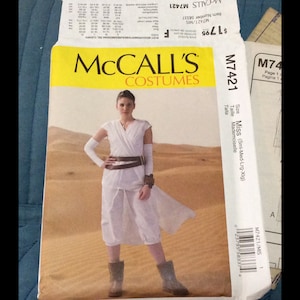 May include: A sewing pattern for a white costume with a brown belt. The pattern is for sizes Small, Medium, Large, and Extra Large. The pattern number is M7421. The pattern is from McCall's Costumes.