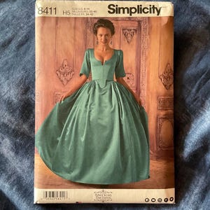 May include: Simplicity sewing pattern number 8411, size US 6-14, for a green gown with a low neckline and a fitted bodice. The pattern is for a historical costume, possibly a ball gown or a dress from the 18th century.
