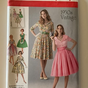 May include: A vintage sewing pattern featuring four different dress designs. The pattern is titled "1950s Vintage" and includes a floral print dress, a solid pink dress, and two other dresses with floral prints.