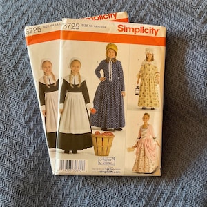 May include: Two Simplicity sewing pattern envelopes for girls' costumes. The pattern number is 3725. The patterns include a pilgrim dress, a colonial dress, and a pioneer dress.