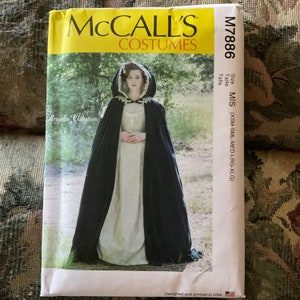 May include: A McCall's Costumes sewing pattern for a black hooded cape. The pattern number is M7886 and the size is MIS (XSM-SML-MED-LRG-XLG). The pattern is designed and printed in the USA.
