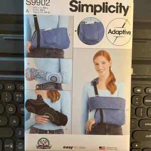 May include: A Simplicity sewing pattern for an adaptive shoulder support. The pattern features a blue denim-like fabric and includes instructions for easy sewing. The package includes the text "easy-to-sew" and "Adaptive".