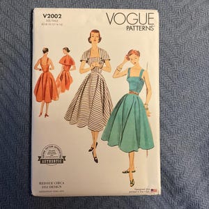 May include: Vogue Patterns sewing pattern, V2002, featuring illustrations of vintage dresses. The cover displays three dress designs in shades of orange, black and white stripes, and teal. The pattern is a reissue from 1952, designed and printed in the USA.