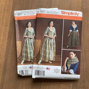 May include: Two Simplicity sewing pattern packets featuring a woman in a colonial-era dress. The patterns include images of the dress in different views. The packets have an orange and white header with the Simplicity logo.