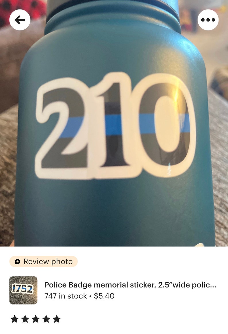 Puede incluir: Una botella de agua azul con una pegatina blanca con el n&uacute;mero "210" en negrita, con una fina l&iacute;nea azul. La pegatina es un homenaje a los agentes de polic&iacute;a.
