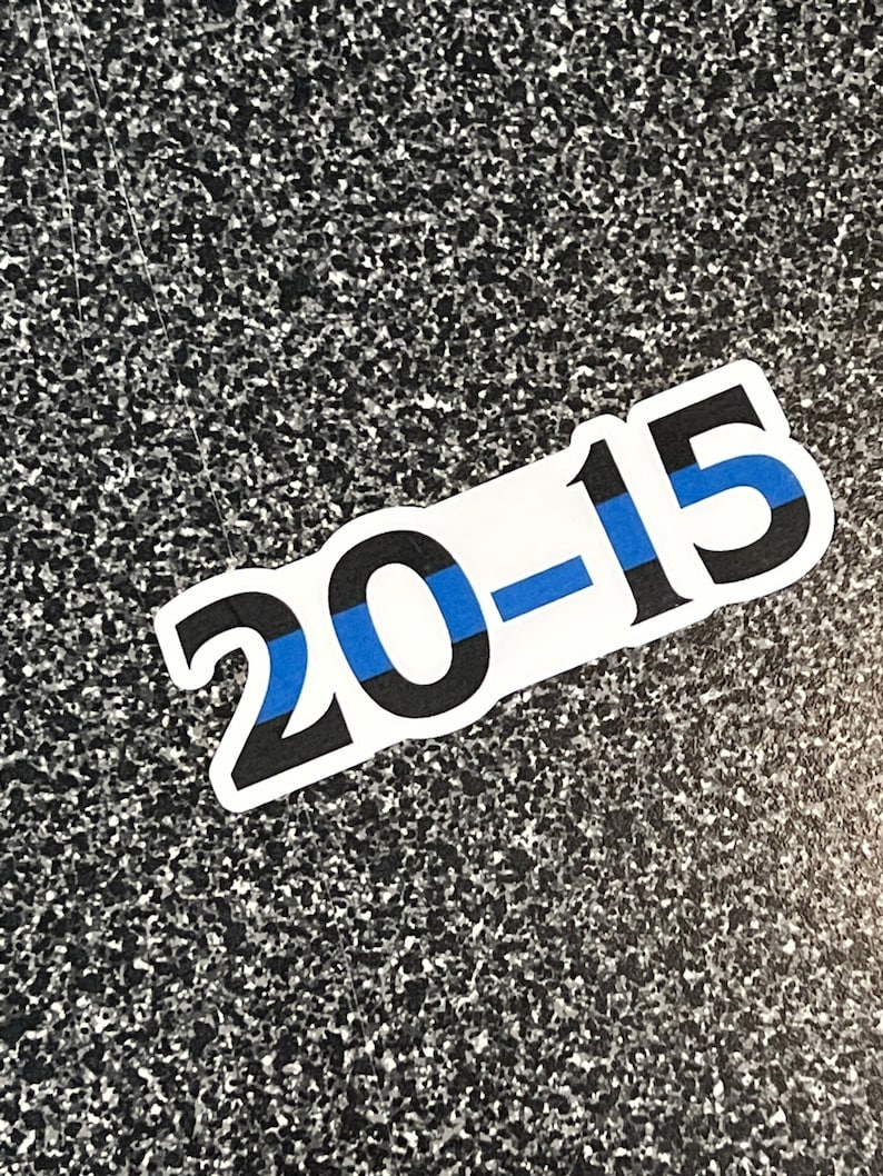 Puede incluir: Adhesivo blanco con el texto "20-15" en negro, con una franja azul. El adhesivo est&aacute; sobre una superficie moteada gris y negra.