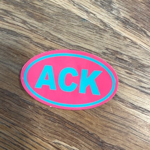 May include: A pink oval sticker with a blue outline and the word "ACK" in blue letters.