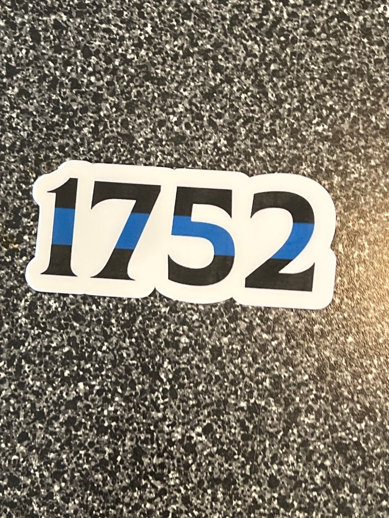 Puede incluir: Adhesivo blanco con el n&uacute;mero 1752 en fuente negra. Una l&iacute;nea azul atraviesa horizontalmente el centro de los n&uacute;meros. El adhesivo tiene un borde blanco y est&aacute; sobre un fondo gris moteado.