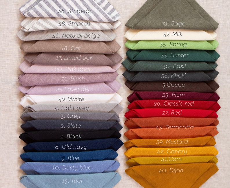 May include: A collection of folded linen napkins in various colors, including sage, red, and blue. Each napkin is labeled with a number and color name, such as "Striped2" and "Dijon". The napkins are neatly stacked, showcasing a range of hues.