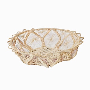 May include: A woven basket with a starburst design. The basket is made of natural materials and has a light brown color.