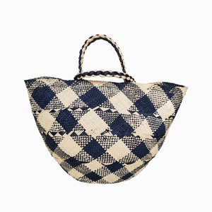 Puede incluir: Un bolso tote grande tejido con un patr&oacute;n de cuadros blanco y negro. El bolso tiene dos asas de cuero negro.