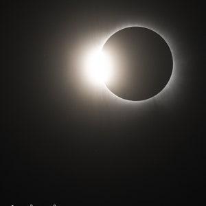 May include: A close-up of a total solar eclipse, showing the sun's corona as a bright ring around the black silhouette of the moon.