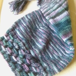 May include: A striped knitted hat with a long tassel in shades of purple, blue, and green.