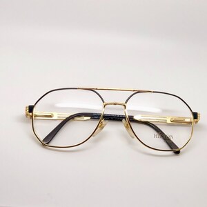 May include: Gold-tone aviator eyeglasses with black arms and a black Hinton Paris logo on the right lens.