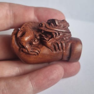 Vintage finely detailed hand-carved boxwood netsuke featuring detailed Japanese dragon curled intricately around a human hand